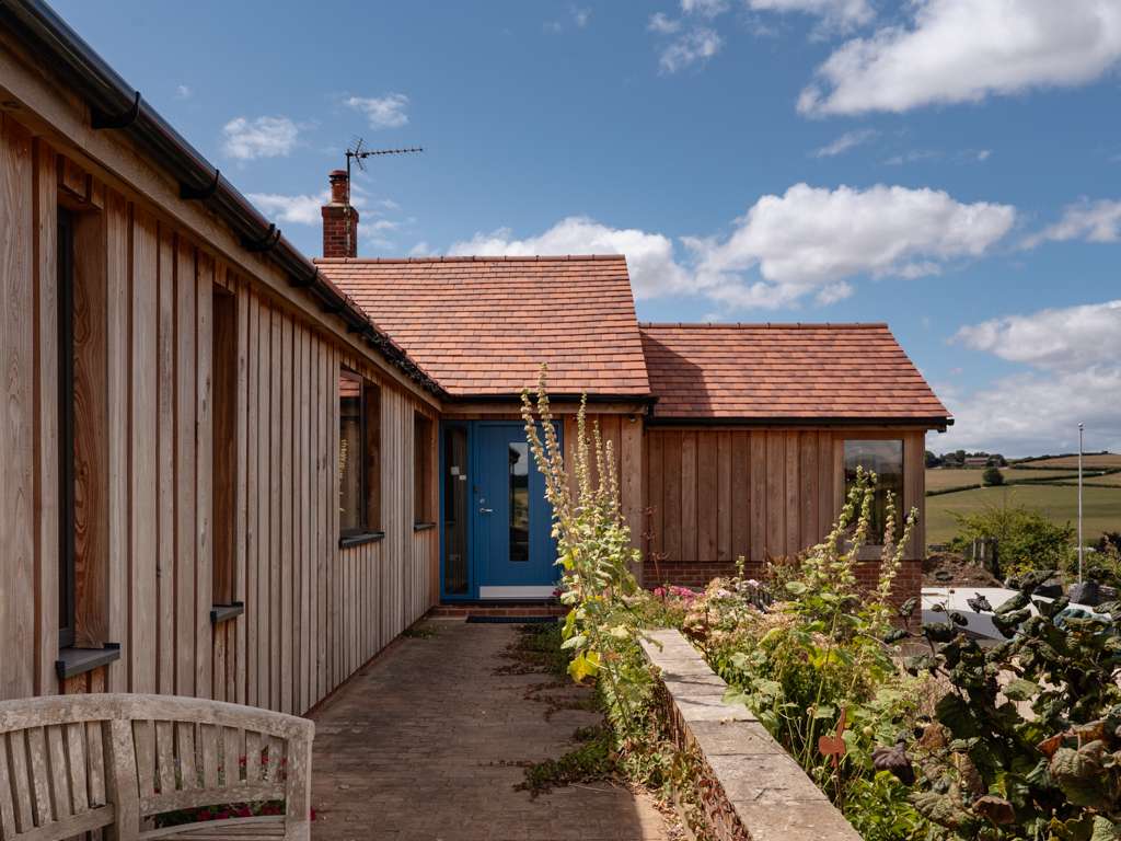Revamped bungalow clad in air-dried larch hit and miss cladding with new Sandtoft 20/20 clay tile roof and oak framed garden room near Blandford, Dorset, renovated by Dorset Timber Framing