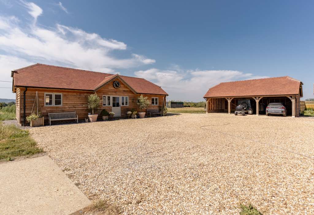 Oak framed two-bedroom annexe and three-bay oak carport with clay plain tile roofs, set around a gravel drive near King’s Stag, Dorset, designed and built by Dorset Timber Framing
