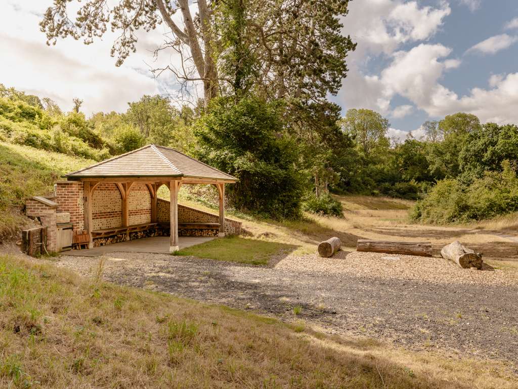 The Rummage Hut, an oak framed shelter with cedar shingle roof set in a remote valley near Stourpaine, Dorset, designed and built by Dorset Timber Framing