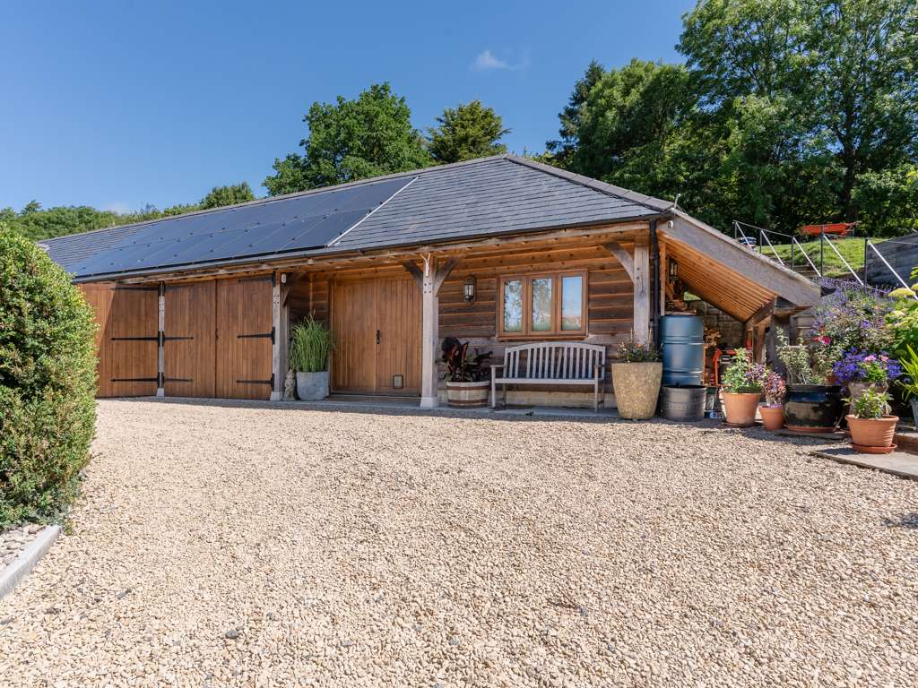 Oak framed outbuilding with Spanish slate roof and solar panels, Siberian larch feather edge cladding and log store, near Shaftesbury, Dorset, designed and built by Dorset Timber Framing