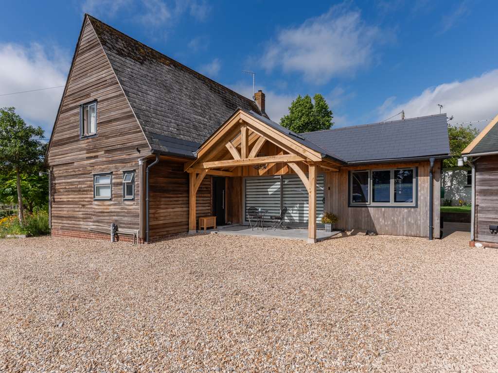 Green oak framed porch with glazed roof sections and fibre cement slate roof over bifold doors, Marnhull, Dorset, designed and built by Dorset Timber Framing